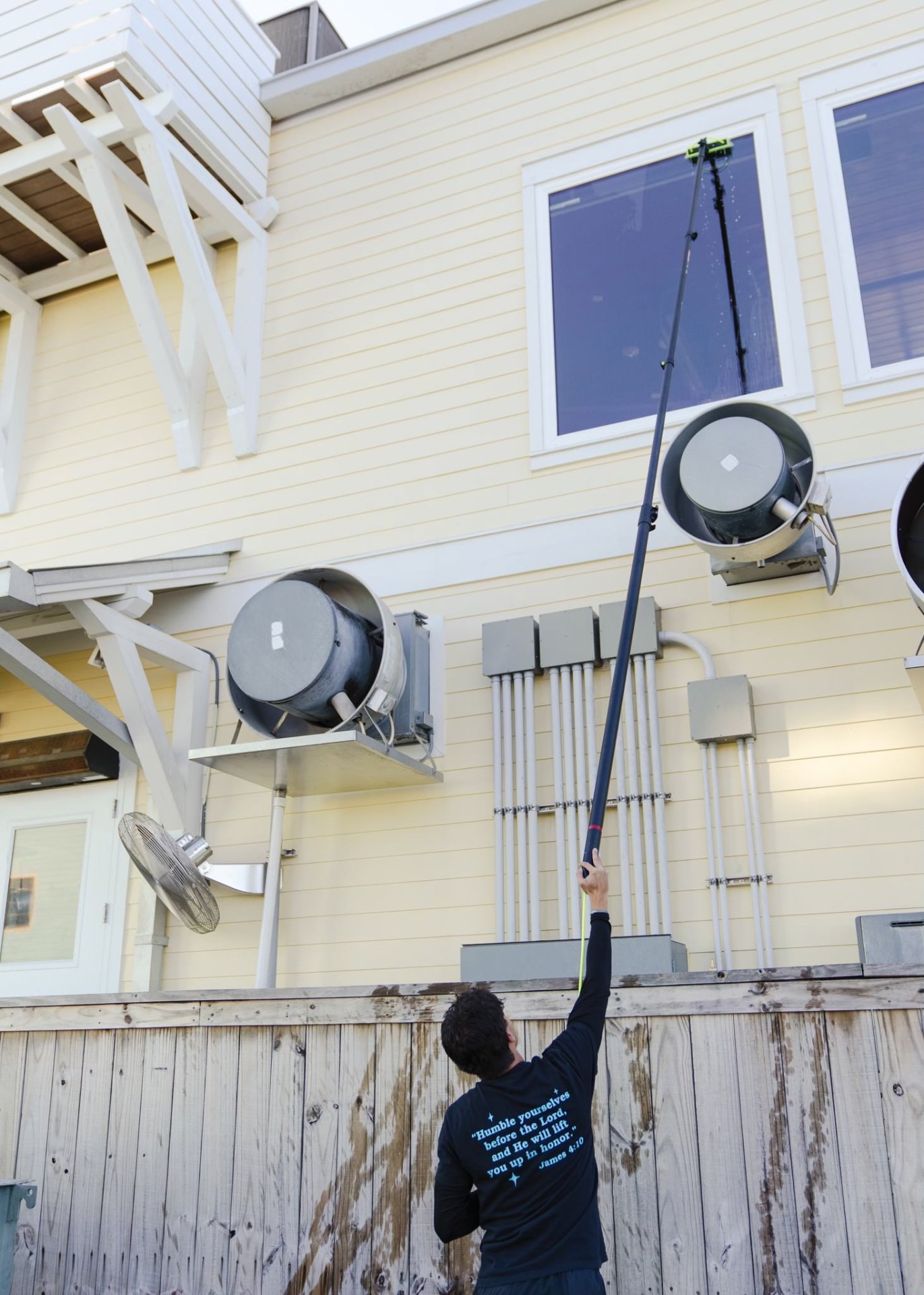 Window cleaning technician reaching second story windows